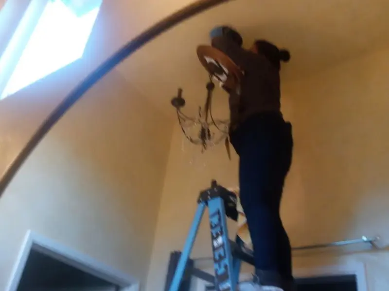 Electrician installing a chandelier in a Raymond residence